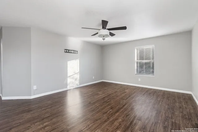 a view of an empty room with wooden floor and a window