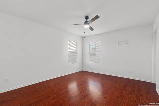 a view of empty room with wooden floor and fan