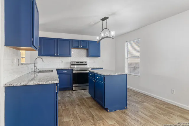 a kitchen with stainless steel appliances granite countertop wooden cabinets a stove a sink and a wooden floors