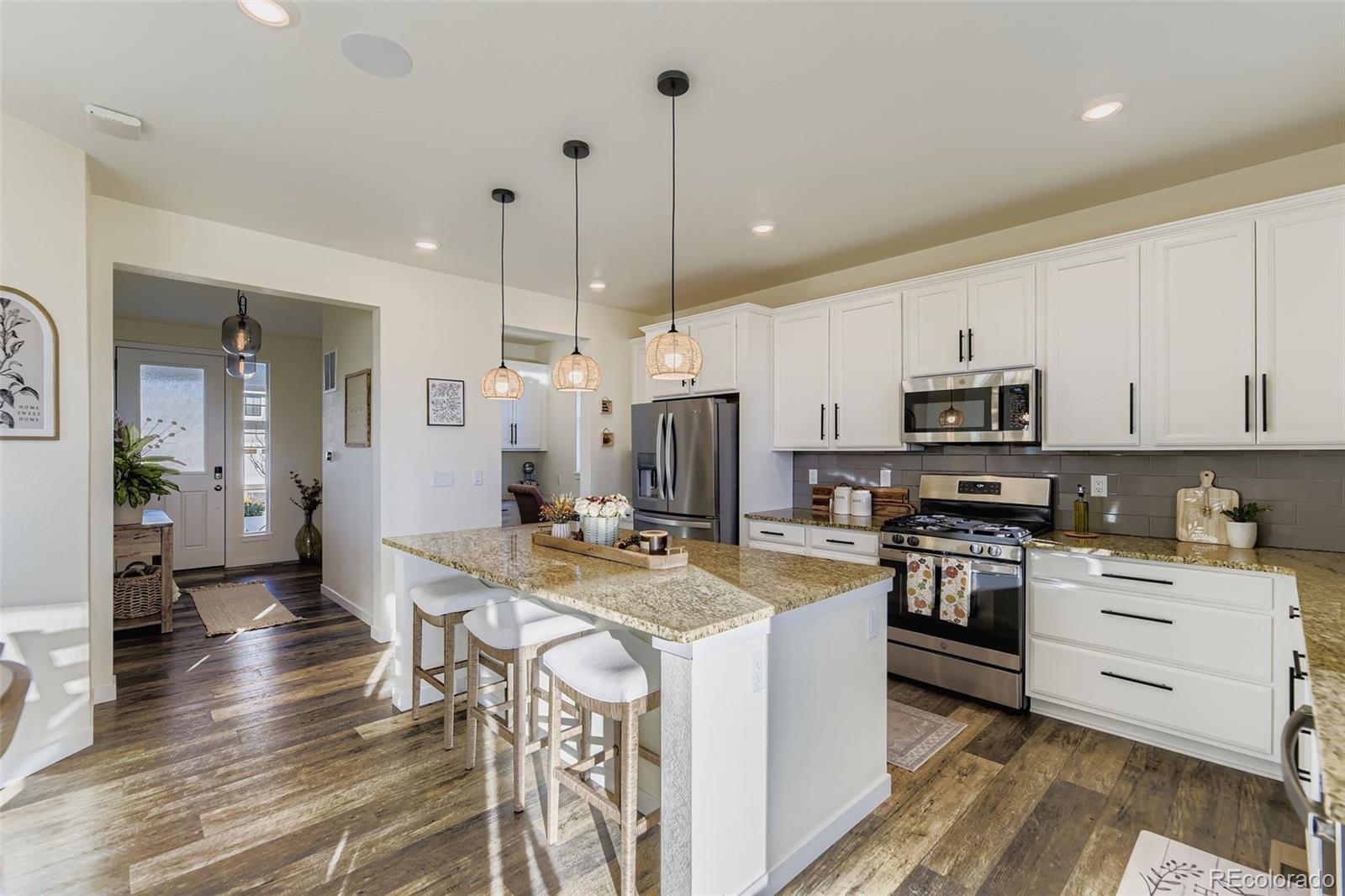1126 Williams Loop Elizabeth, CO 80107 - Photo 11 of 50 a kitchen with stainless steel appliances kitchen island granite countertop a stove a sink a refrigerator and white cabinets with wooden floor