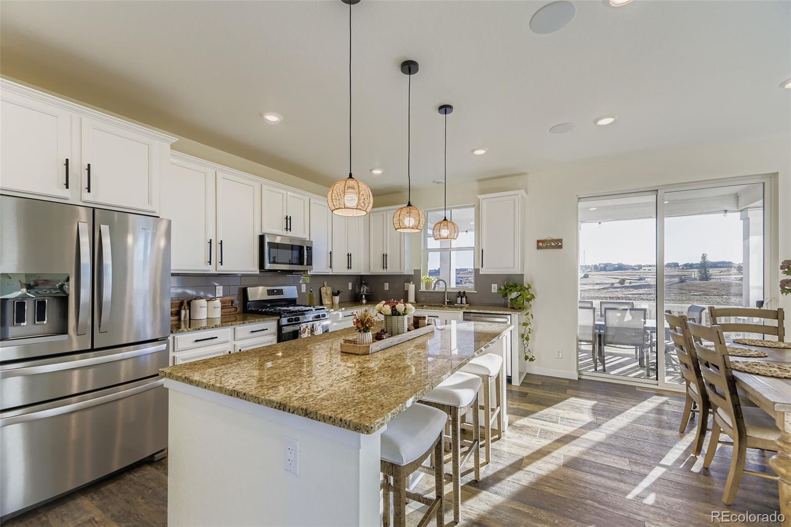 1126 Williams Loop Elizabeth, CO 80107 - Photo 9 of 50 a kitchen with stainless steel appliances granite countertop a stove a refrigerator a kitchen island a table and chairs