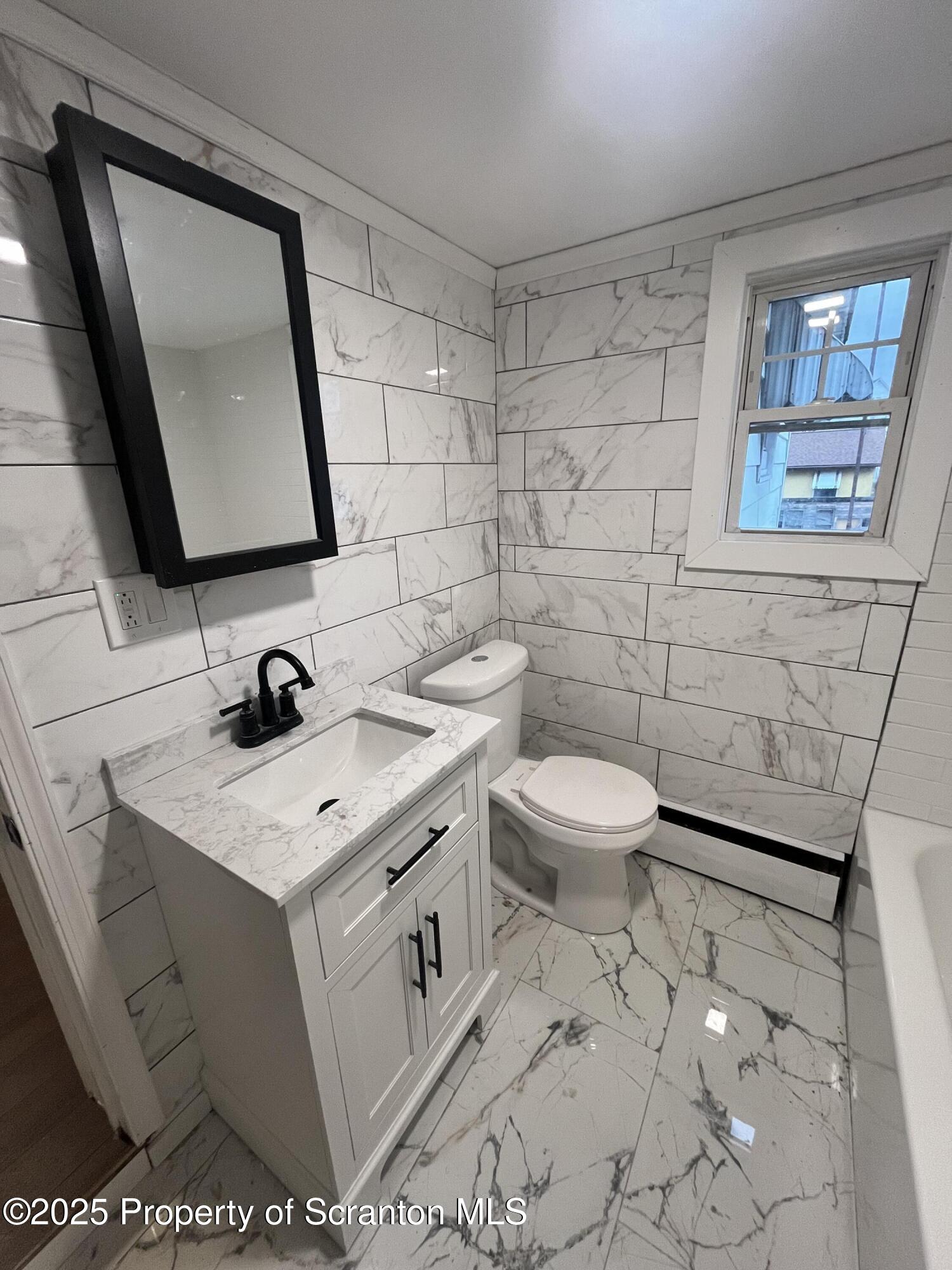 129 South Blakely Street, Unit 2 Dunmore, PA 18512 - Photo 2 of 10 a bathroom with a toilet sink and mirror