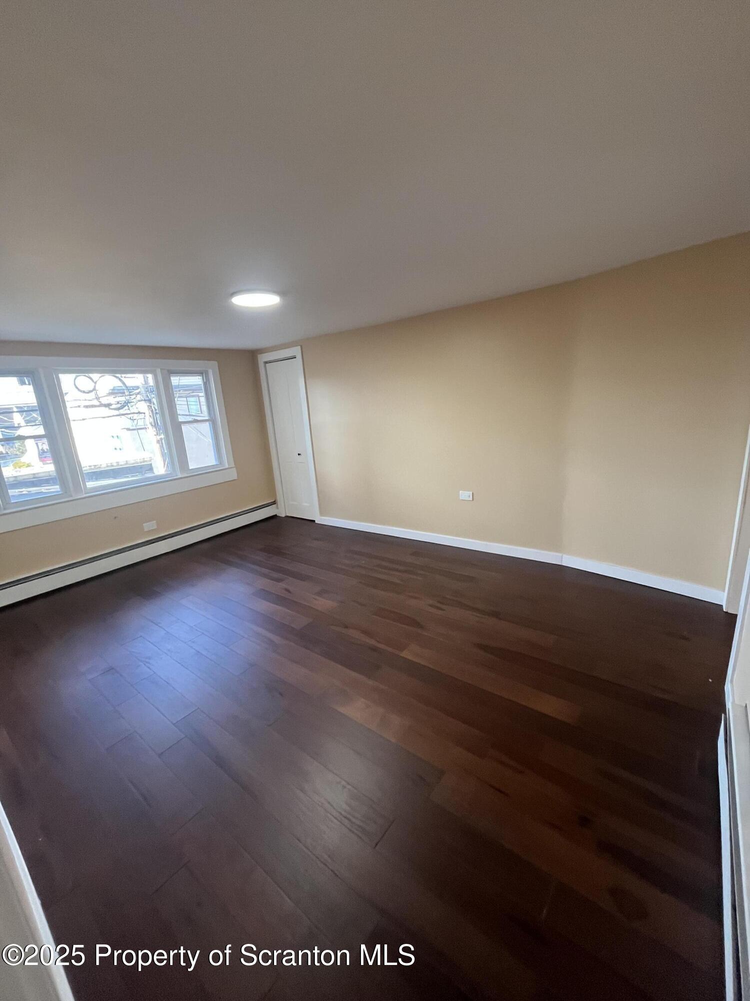 129 South Blakely Street, Unit 2 Dunmore, PA 18512 - Photo 6 of 10 an empty room with wooden floor and windows