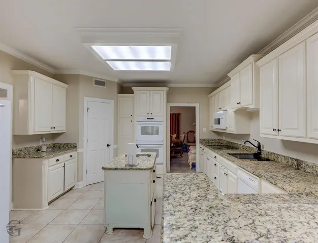 a kitchen with granite countertop a sink stove and cabinets