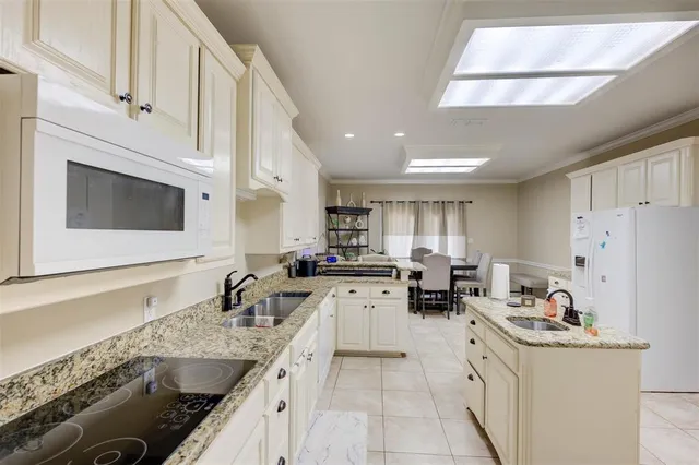 a kitchen with granite countertop a sink dishwasher stove and white cabinets