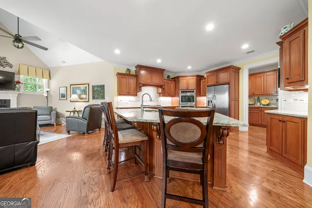 a kitchen with stainless steel appliances kitchen island granite countertop a table chairs in it and wooden floors