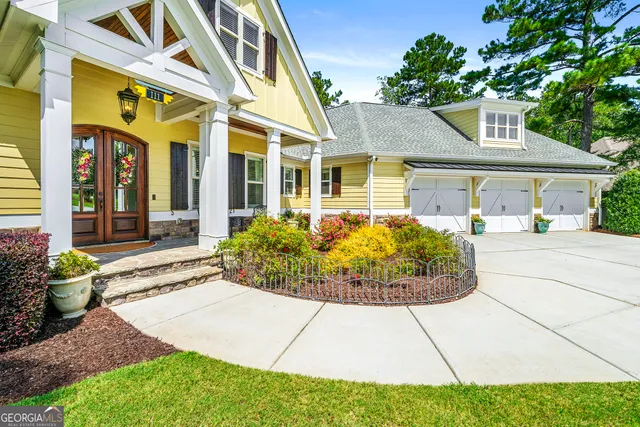 a view of a white house with potted plants and a dining table