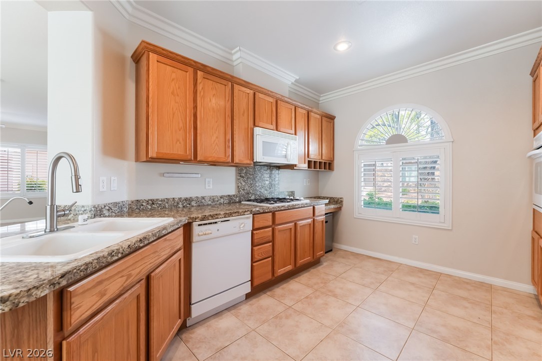 10481 Riverside Park Avenue Las Vegas, NV 89135 - Photo 12 of 51 Kitchen featuring white appliances, wood finish cabinetry, crown molding, decorative backsplash, and dark stone countertops