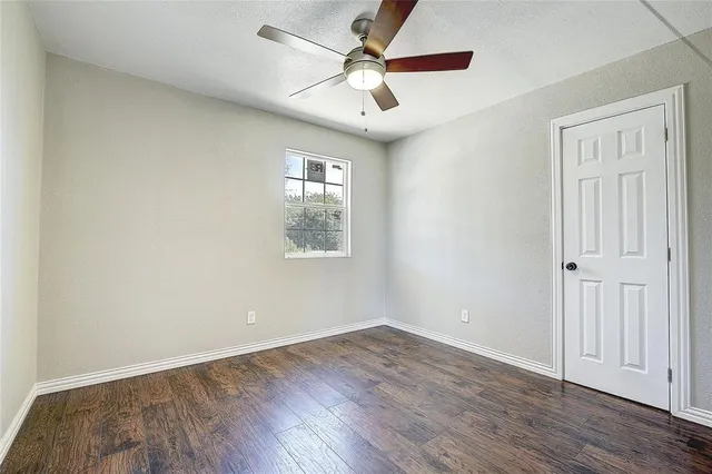 an empty room with wooden floor ceiling fan and windows