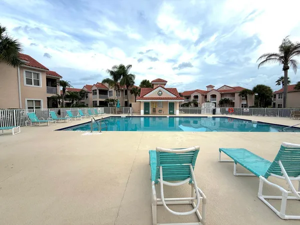 a view of swimming pool of water with lawn chairs and large tree