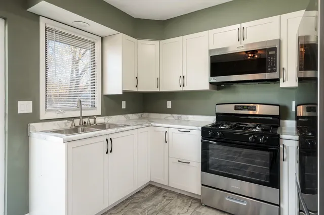 a kitchen with stainless steel appliances granite countertop a stove a microwave and a sink