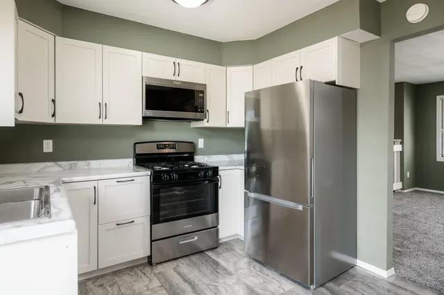 a kitchen with stainless steel appliances white cabinets and a refrigerator