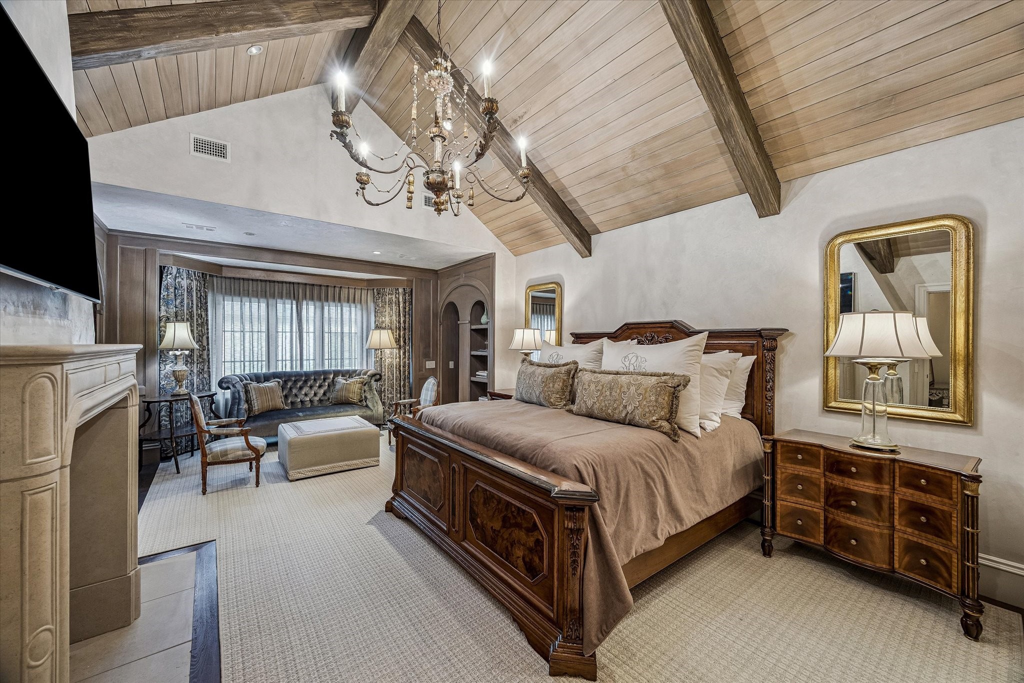 2158 Chilton Road Houston, TX 77019 - Photo 31 of 50 The primary bedroom is a serene retreat featuring vaulted, beam-accented ceilings, Segreto plaster walls, and a cast stone fireplace. Custom remote-controlled draperies, designer lighting, and in-ceiling speakers create a luxurious and comfortable living space.