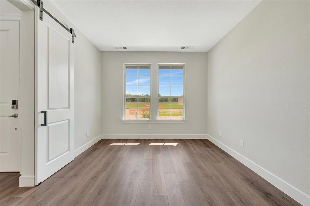 11460 Wulstone Road Fort Worth, TX 76052 - Photo 19 of 40 a view of an empty room with wooden floor and a window