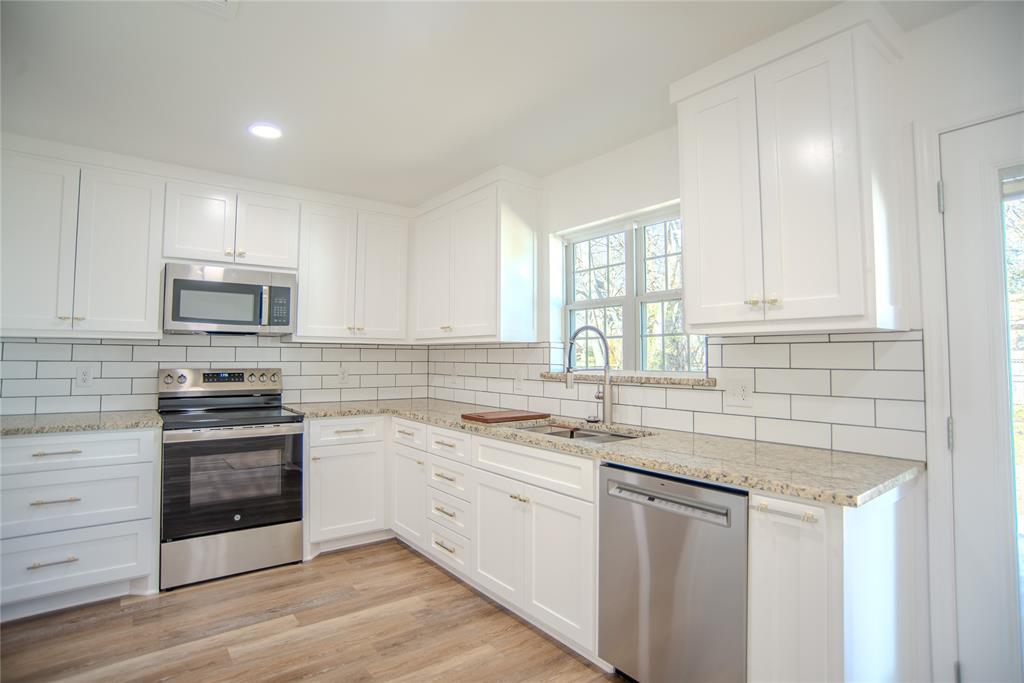 1805 Belden Street Sherman, TX 75092 - Photo 7 of 16 a kitchen with stainless steel appliances granite countertop a sink stove oven and white cabinets