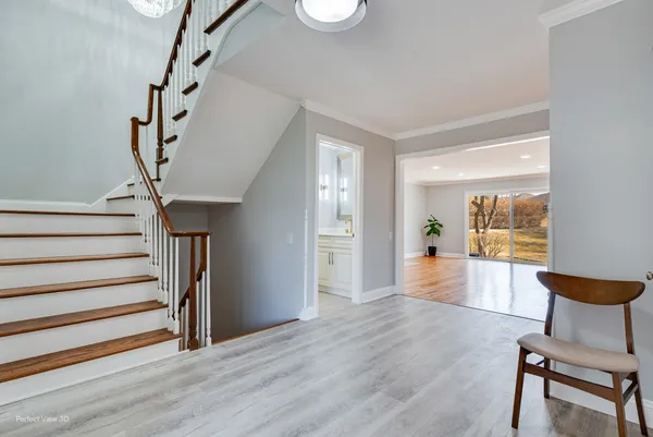 a view of a hallway to a livingroom with furniture stairs wooden floor and windows