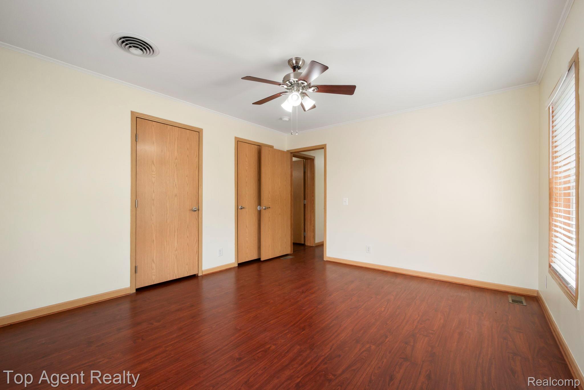 2018 John R Road Troy, MI 48083 - Photo 18 of 30 Unfurnished bedroom featuring dark wood-style flooring, ornamental molding, multiple closets, and a ceiling fan