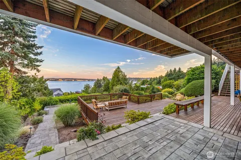 a view of a patio with couches and table and chairs with wooden floor and fence