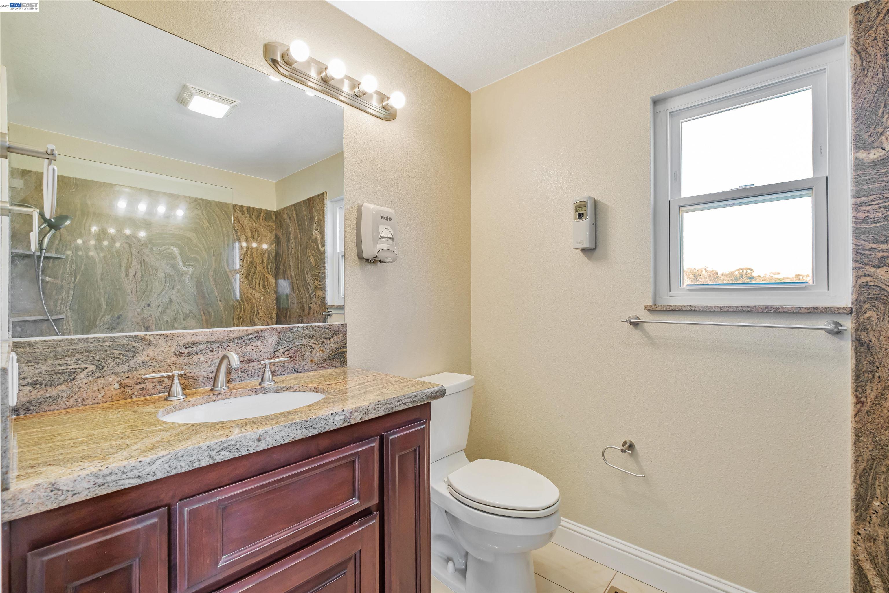 41794 Vargas Road Fremont, CA 94539 - Photo 47 of 60 a bathroom with a granite countertop sink a mirror and a toilet