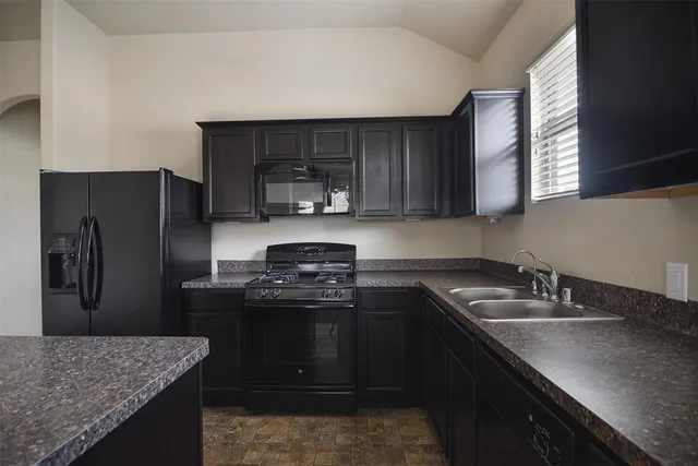 a kitchen with stainless steel appliances granite countertop a stove a sink and a refrigerator