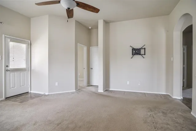 an empty room with a ceiling fan and windows
