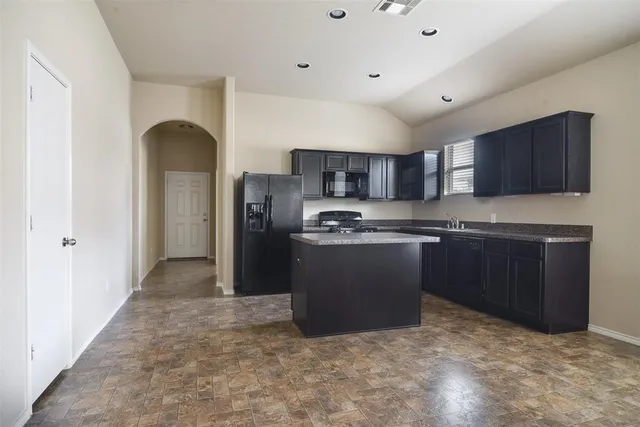 a kitchen with granite countertop a sink stove and refrigerator