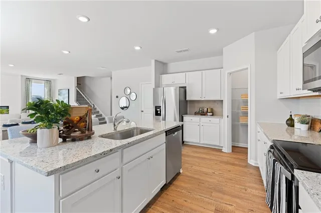 a kitchen with white cabinets and wooden floor