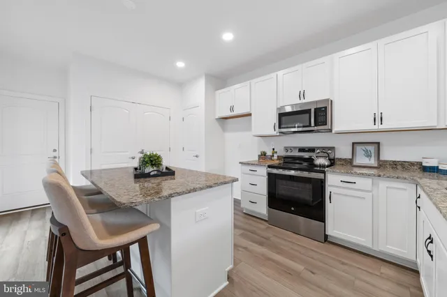 a kitchen with granite countertop a sink stove and white cabinets