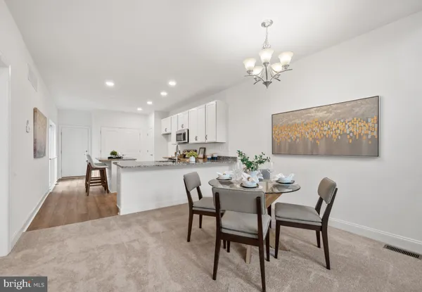 a dining room with wooden floor a chandelier a wooden table and chairs