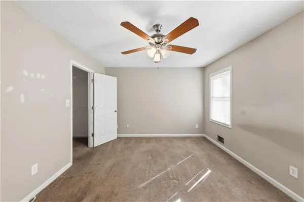 a view of an empty room with window and ceiling fan