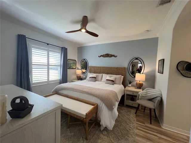 a spacious bedroom with a bed a mirror and windows