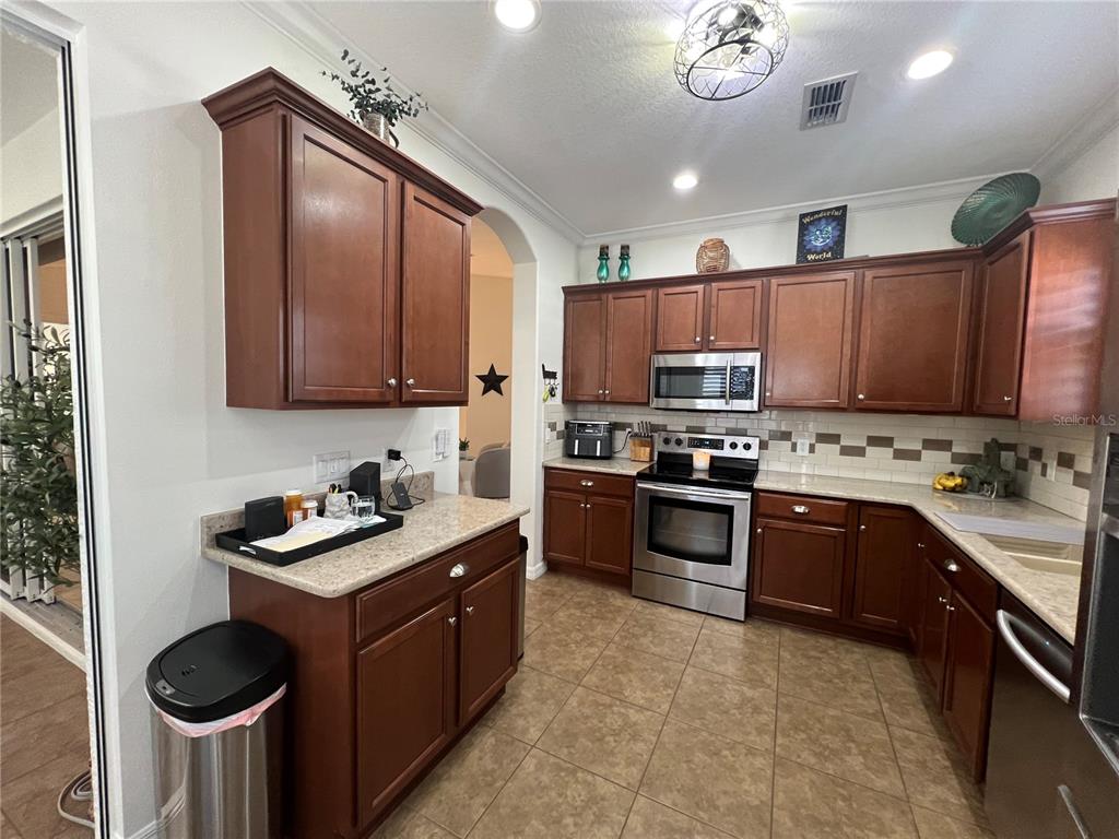 24401 Manchester Trail Port Charlotte, FL 33980 - Photo 21 of 47 a kitchen with stainless steel appliances granite countertop wooden cabinets a stove top oven a sink and dishwasher