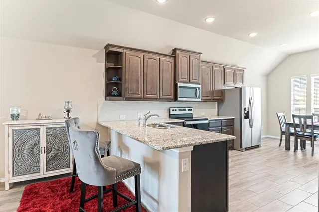 a kitchen with stainless steel appliances granite countertop a table chairs sink refrigerator and cabinets