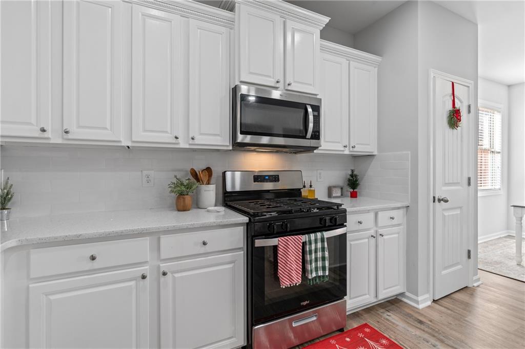 2190 Leatherstone Drive Powder Springs, GA 30127 - Photo 11 of 38 a kitchen with stainless steel appliances granite countertop a stove a microwave and a white cabinets