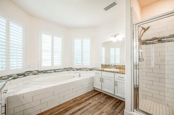 a spacious bathroom with a double vanity sink a mirror and a bathtub