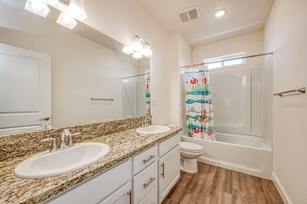 a bathroom with a granite countertop sink a toilet a shower and a mirror
