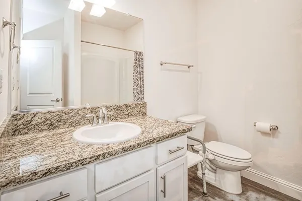 a bathroom with a granite countertop sink a toilet and a mirror