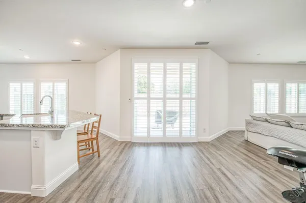 a large kitchen with stainless steel appliances a large window a sink and wooden floor