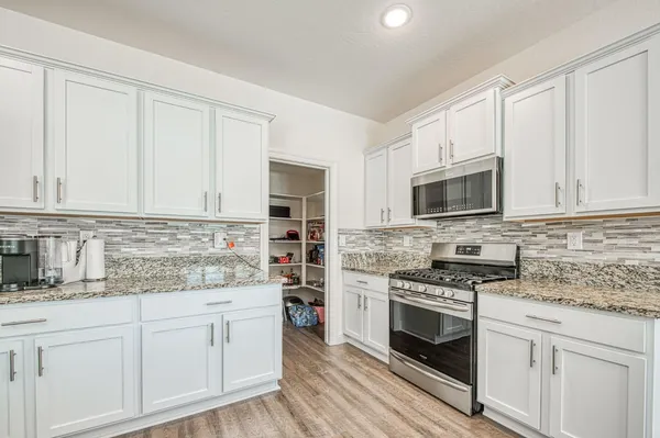 a kitchen with granite countertop white cabinets and appliances