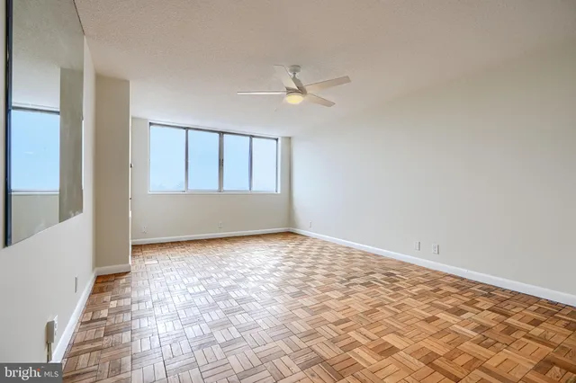 a view of empty room with wooden floor and fan