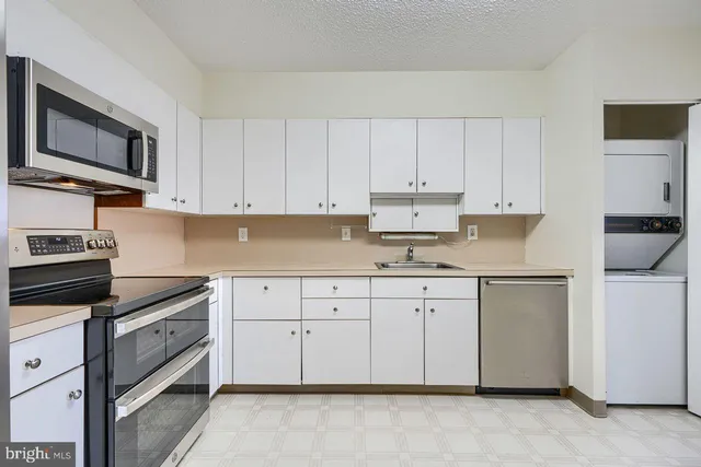 a kitchen with granite countertop white cabinets sink and stainless steel appliances
