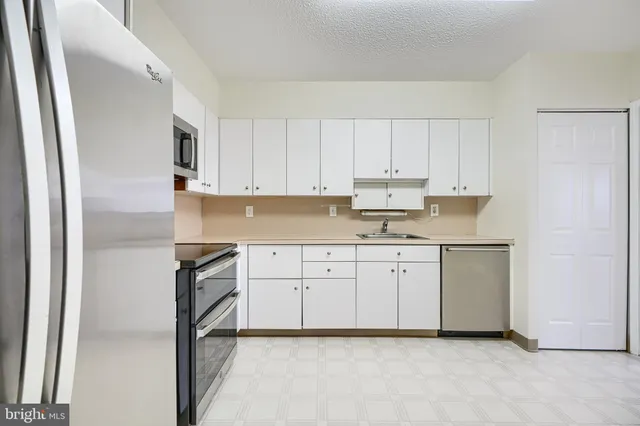 a kitchen with granite countertop white cabinets and white stainless steel appliances