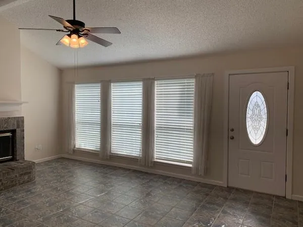 an empty room with windows and fan