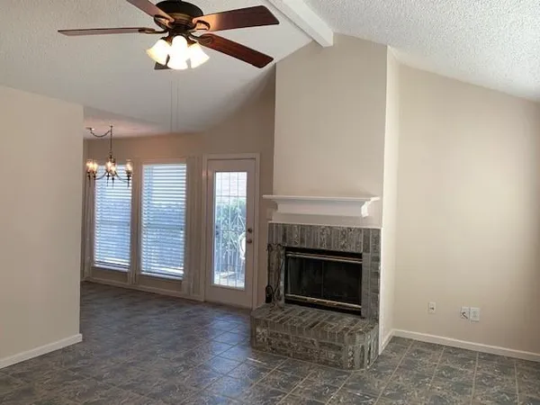 an empty room with windows fireplace and fan