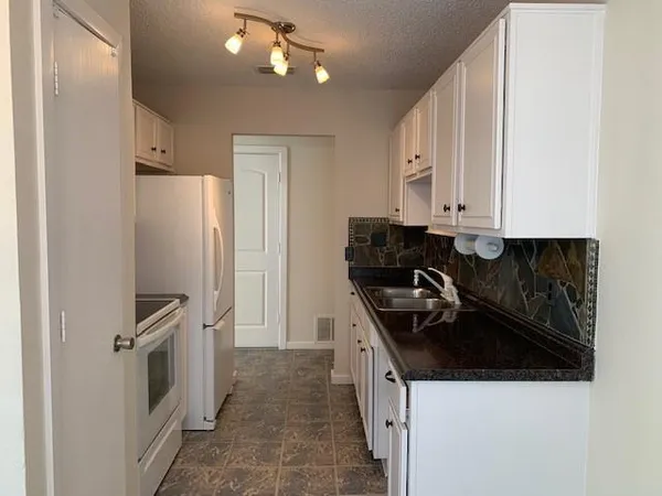 a view of a kitchen with refrigerator and cabinets