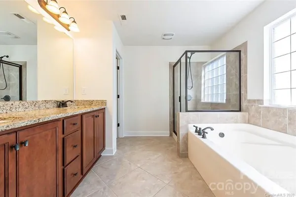 a spacious bathroom with a granite countertop tub sink and mirror