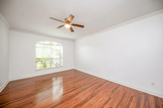 a view of empty room with wooden floor and fan