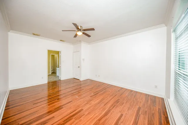 a view of empty room with wooden floor and fan