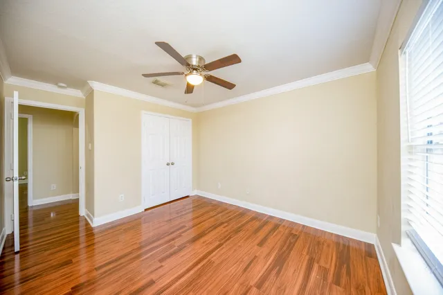 a view of empty room with wooden floor and fan