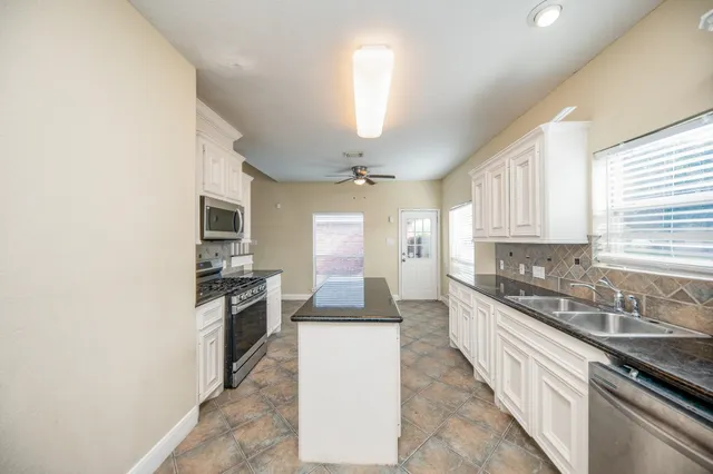 a large kitchen with granite countertop a stove top oven a sink a dining table and chairs